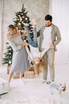 Happy family: mom, dad and pet. Family in a bright New Year's interior with a Christmas tree.