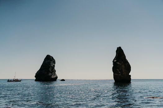 Two rocks stick out of the water in the middle of the turquoise sea. Scenic ocean views. High quality photo. Like in Iceland.
