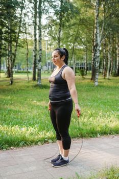 A charming brunette woman plus-size body positive practices sports in nature.