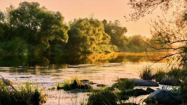 the time in the evening when the sun disappears or daylight fades.Wonderful fast flowing quiet river in the golden rays of the setting sunset sun