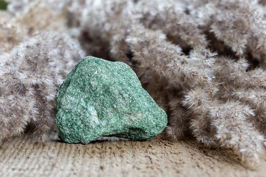 Fuchsite mineral or green muscovite stone over natural background. Mudcovite or chrome mica mineral rock. Natural gemstone collection 