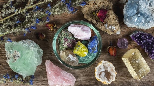 Alternative crystal healing therapy concept. Stones and minerals set up on the wooden table with dry flowers. Gemstones for esoteric spiritual practice or witchcraft 