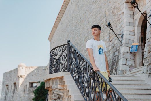 A handsome young man standing and smiling happily in the background of urban buildings. Forty years old caucasian tourist man outdoor near old city buildings - summer holiday.