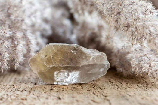 quartz with rutile crystal mineral stone over natural wooden background 