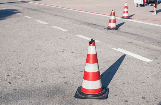 Traffic cone with white and red stripes on the road of the airport. Safety cone.