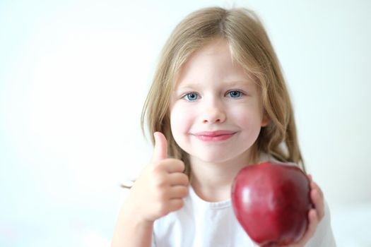 Little beautiful beautiful chooses red tasty juicy apple. Happy child smiles and holds red apple