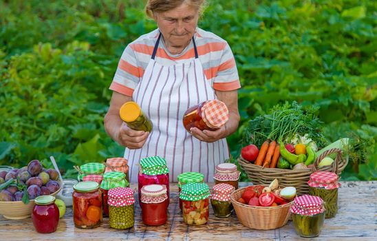 Senior woman preserving vegetables in jars. Selective focus. Food.