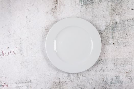 A grey stone surface with white dinner plate place setting