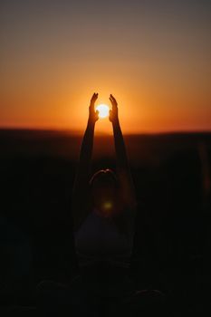 Silhouette of Unrecognisable Woman Catching the Sun That Going Under Horizon by Hands at Sunset