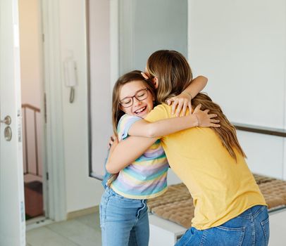 Portriat of a young teen school girl with backpack welcomed by her mother after coming back from school at home