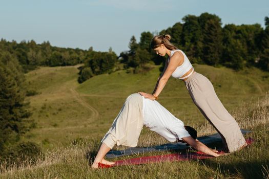 Young Adult Couple, Man and Woman Practicing Yoga Outdoors with Scenic Landscape on Background