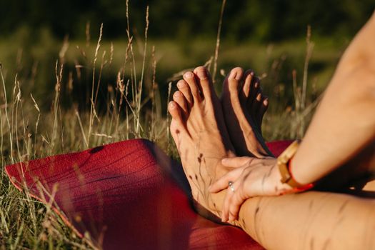 Close Up Unrecognisable Woman Holding Her Feet While Sitting on Mat During Yoga Outdoors at Sunset