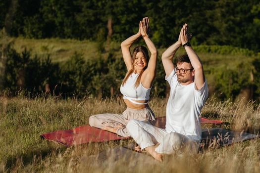 Cheerful Woman and Happy Man Raising Hands Up Over Heads, Young Adult Couple Meditating Outdoors in Nature