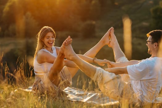 Young Adult Couple Practicing Yoga Outdoors in Nature, Cheerful Woman and Happy Man Doing Exercise Together at Sunset