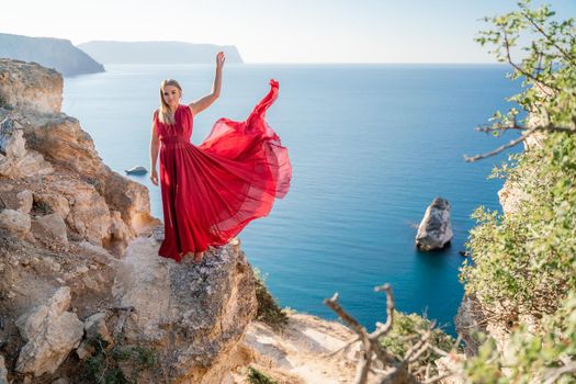 A woman in a red flying dress fluttering in the wind, against the backdrop of the sea