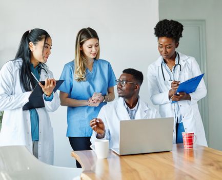 portrait of a doctors and nurses with laptop sitting by desk on their office