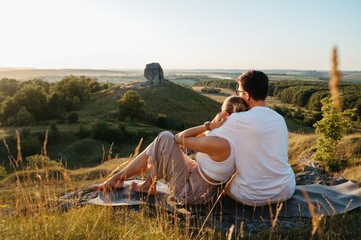 Man and Woman Enjoying Picnic with Beautiful Sunset Outdoors, Scenic Landscape and Nature Miracle Giant Stone on Background