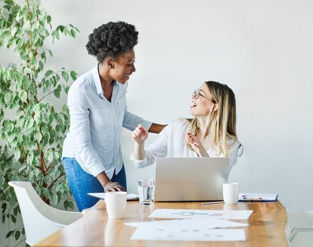 Portrait of two of young businesswomen multiethnic working with laptop on desk and talking in a start up office