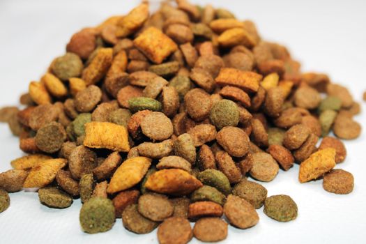 Dry food for cats, dogs lies in a pile on a light background. Close-up. Blurred background and background.