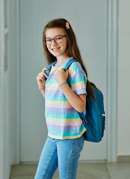 Portriat of a young teen school girl with backpack ready for school at home