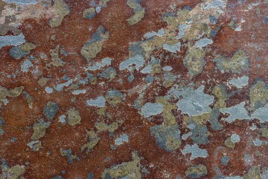 Abstract background of peeling old brown paint with blue spots showing through.