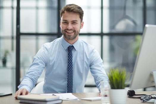 Young cheerful businessman working at office