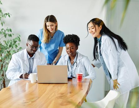 portrait of a doctors and nurses with laptop sitting by desk on their office