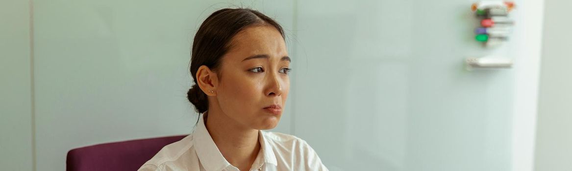 Sad asian business woman sitting on her workplace in office. High quality photo