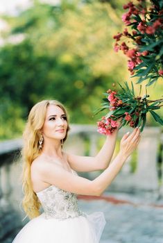 Bride holds in her hands a branch of a flowering pink tree. High quality photo