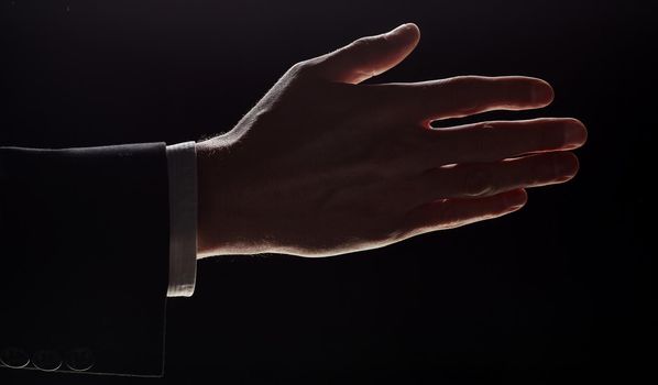 A man holds out his hand for a handshake, highlighted on a black background