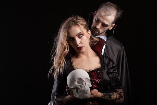 Portrait of young man dressed up like Dracula looking at the neck of his vampire woman. Handsome man and misetrious man dressed up for halloween.