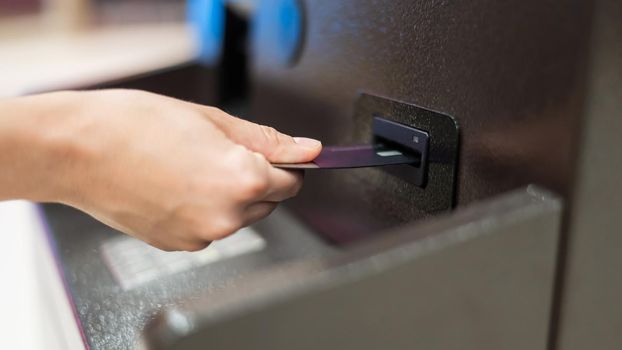 Faceless woman inserts bank card at ATM
