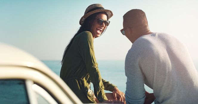 The right guy will make you laugh. a young couple making a stop at the beach while out on a road trip