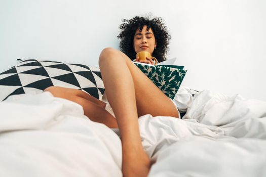 Young mixed race woman relaxing at home drinking tea and writing on journal.Lifestyle concept