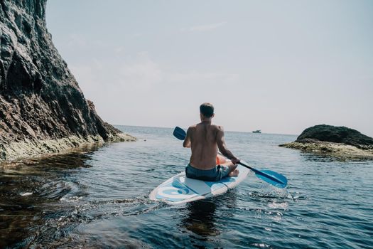 Side view foto of a man swiming and relaxing on the sup board. Sportive man in the sea on the Stand Up Paddle Board SUP. The concept of an active and healthy life in harmony with nature