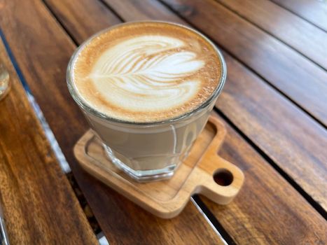 beautiful cup of cappuccino coffee with latte art in the wooden space background