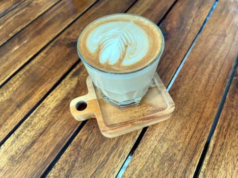 beautiful cup of cappuccino coffee with latte art in the wooden space background