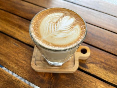 beautiful cup of cappuccino coffee with latte art in the wooden space background