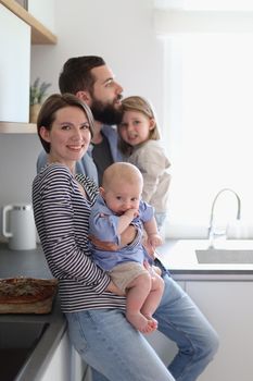 Family of 4 posing in the kitchen smiling and happy