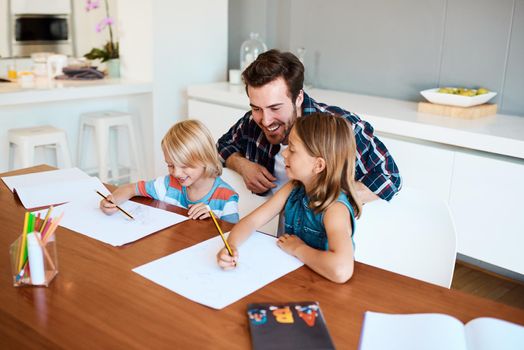 Helping them discover all their hidden talents. a young father helping his two small children with their homework at home