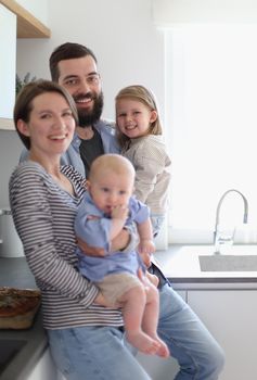 Family of 4 posing in the kitchen smiling and happy