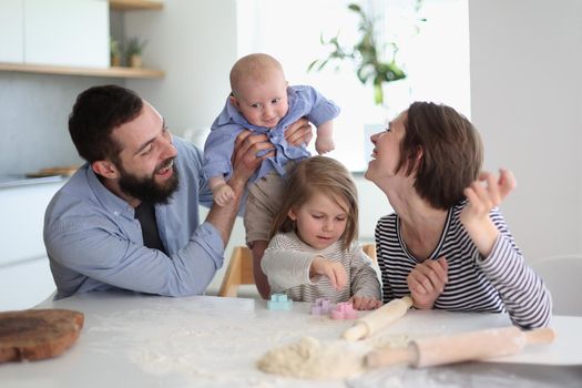 Happy parents playing with their children in the kitchen