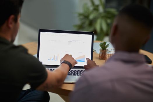 Putting the focus on finance. two young businessmen using a laptop with graphs on the screen during a meeting in a modern office