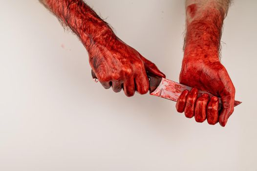 A man with bloody hands cuts himself with a knife