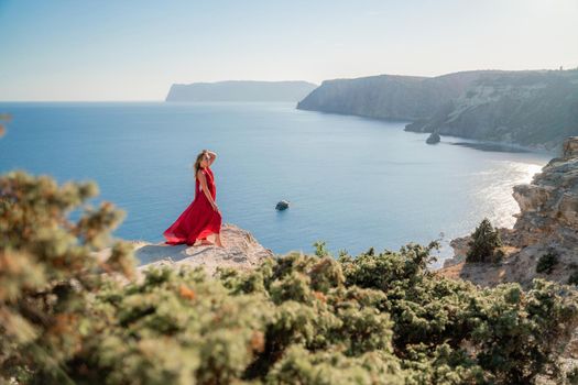 A woman in a red flying dress fluttering in the wind, against the backdrop of the sea