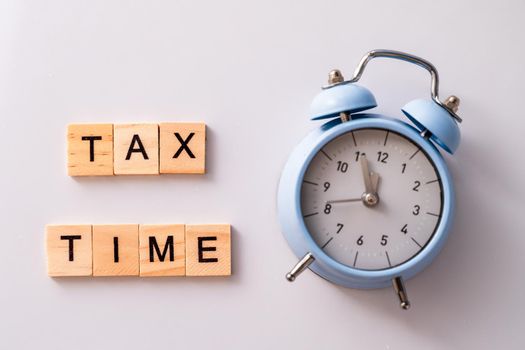 Close-up of alarm clock next to tax time concept on chalkboard.