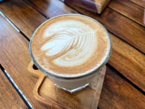 beautiful cup of cappuccino coffee with latte art in the wooden space background