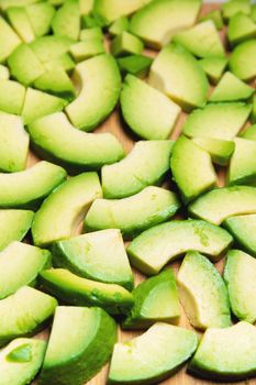 sliced avocado into small pieces lie on a cutting wooden board. copy space.