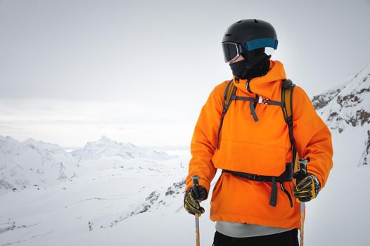 Portrait of a male skier at the top against the backdrop of epic mountains in the clouds