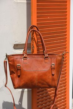 close-up photo of orange leather bag on a wooden blinds. outdoors photo